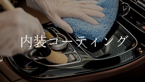 Hands wearing gloves wiping a car interior with a microfiber cloth, highlighting an interior coating service.